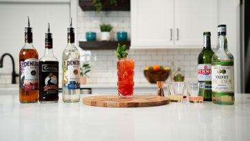 a glass of zombie cocktail with recipe ingredients at the background